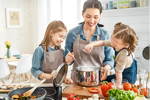 Dieta na odporność - co i jak jeść, aby wzmocnić odporność? Mama z dwiema córeczkami w kuchni przygotowuje zdrowy posiłek.