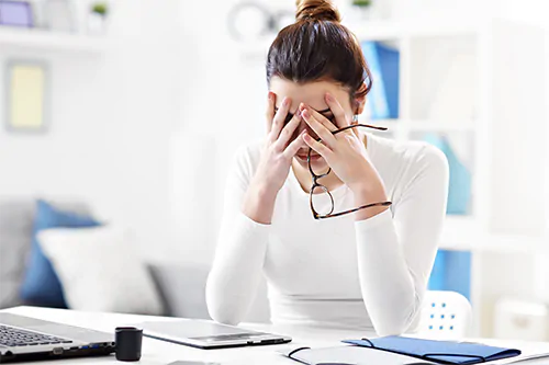 Jak stres wpływa na organizm? Jak radzić sobie ze stresem? Kobieta skrywa głowę w dłoniach z powodu stresu w pracy.