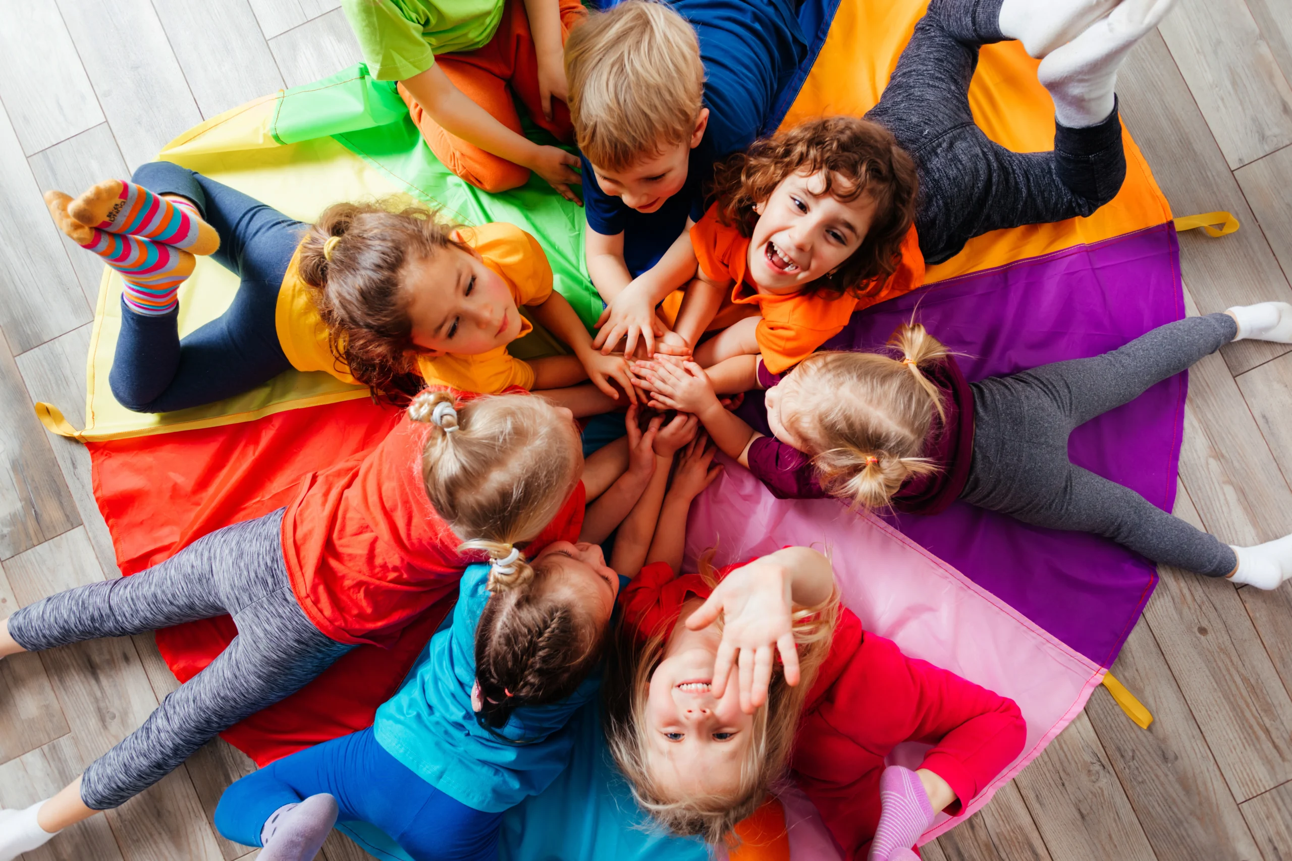 Jak wesprzeć brzuszek dziecka w pierwszych dniach przedszkola? Grupa dzieci w wieku przedszkolnym bawi się ze sobą w kółku.