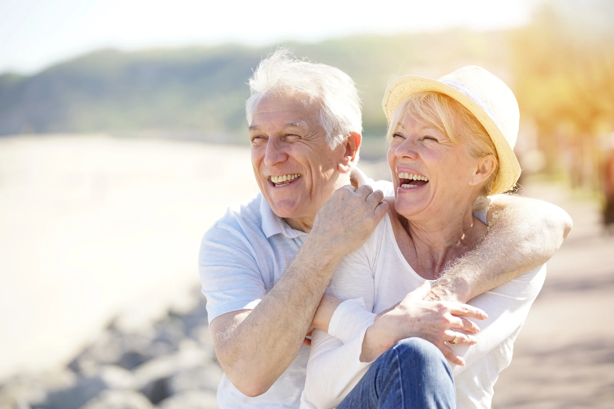 Jakie są sposoby na długowieczność? Co charakteryzuje tzw. blue zones, gdzie żyje najwięcej stulatków? Para uśmiechniętych seniorów na plaży.